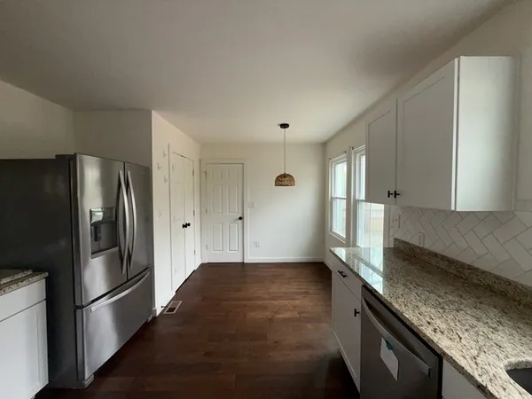 a kitchen with granite countertop a refrigerator and a stove top oven