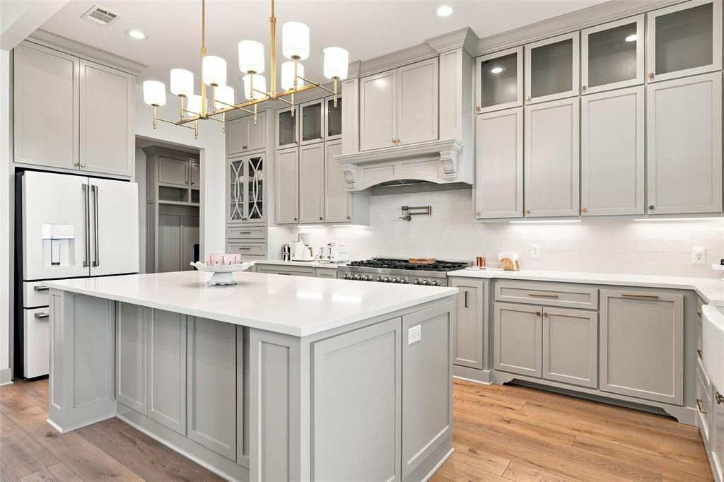 803 Willow Moon Ranch Road Crawford, TX 76638 - Photo 12 of 37 Modern kitchen featuring light gray cabinetry, a central island with a solid surface countertop, wood-finish flooring, a stainless steel range, and a subway tile backsplash