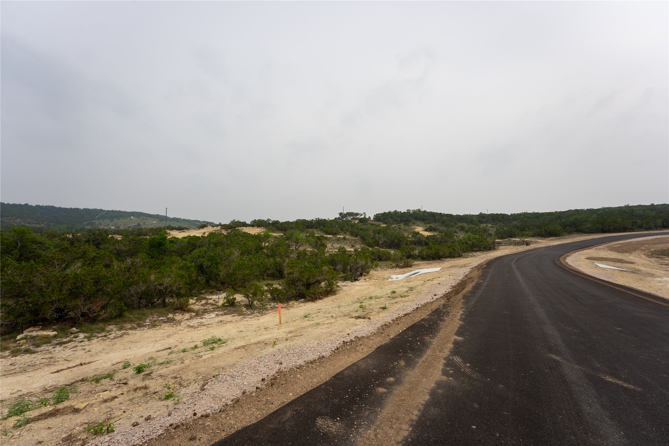Lot 3 Ranch Road 165 Dripping Springs, TX 78620 - Photo 8 of 11 Newly paved asphalt road bordering natural terrain and distant treeline