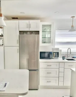 a kitchen with white cabinets and refrigerator