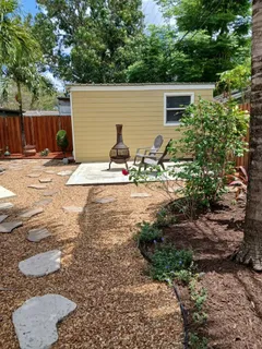 a view of a backyard with plants and large tree