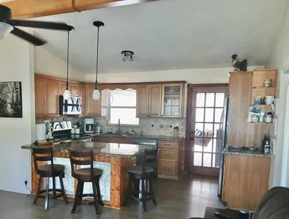 a dining hall with stainless steel appliances granite countertop a dining table and chairs with wooden floor