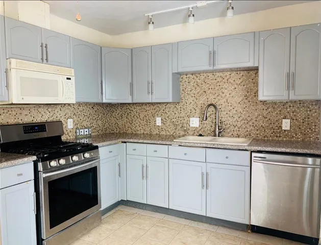 a kitchen with granite countertop white cabinets and black appliances