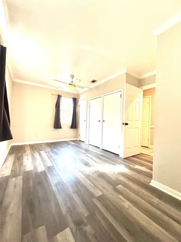 a view of empty room with wooden floor and fan