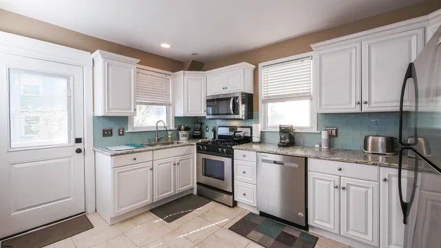 a kitchen with granite countertop white cabinets sink and stainless steel appliances