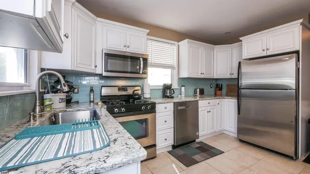 a kitchen with granite countertop a refrigerator stove and sink