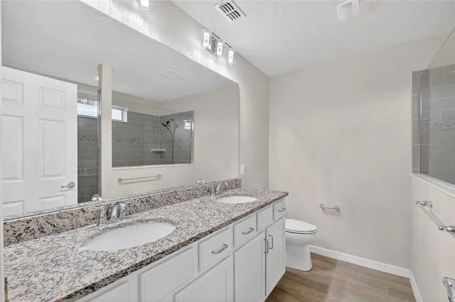 a bathroom with a granite countertop double vanity and a mirror