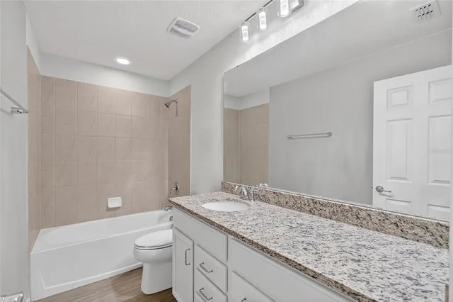 a bathroom with a granite countertop sink a toilet and bathtub