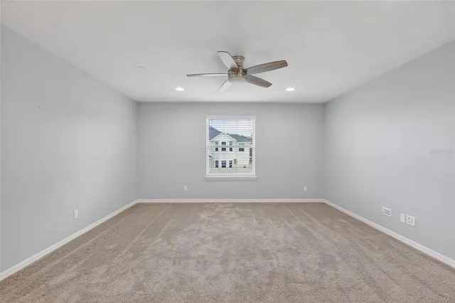 an empty room with a ceiling fan and window