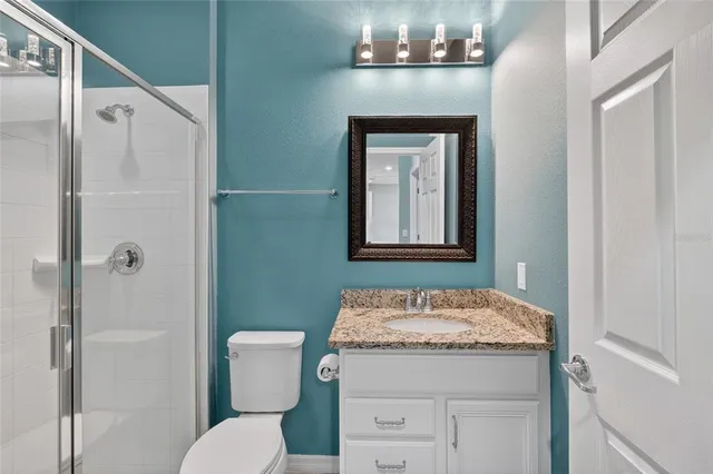 a bathroom with a granite countertop sink toilet and shower
