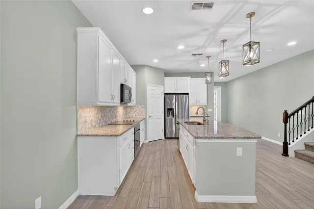 a kitchen with stainless steel appliances granite countertop a sink and a refrigerator