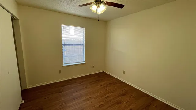 a view of a room with wooden floor and a chandelier fan