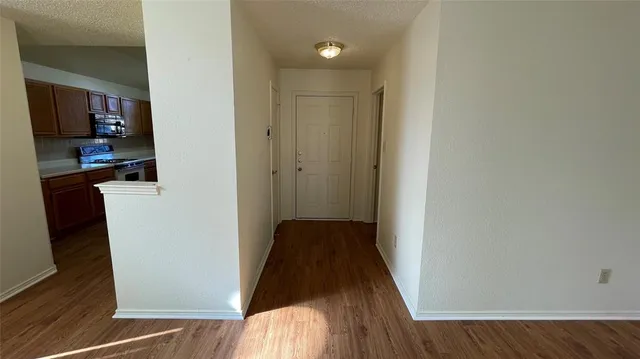 a view of a hallway with wooden floor and a bathroom