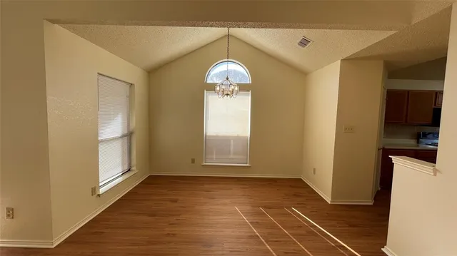 a view of a room with wooden floor a kitchen space with a sink and a window