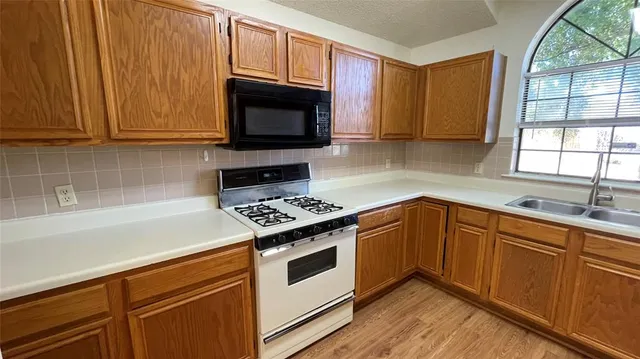 a kitchen with granite countertop wooden cabinets appliances and a window
