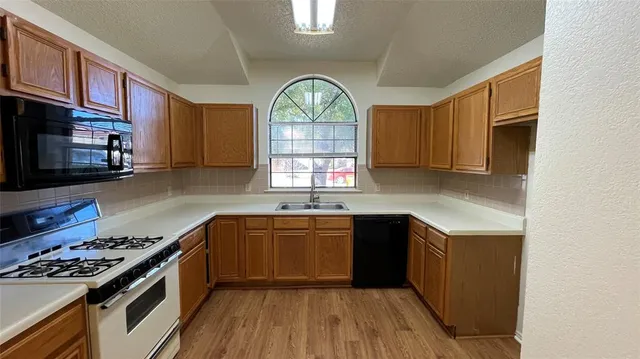 a kitchen with stainless steel appliances granite countertop wooden cabinets stove top oven and sink