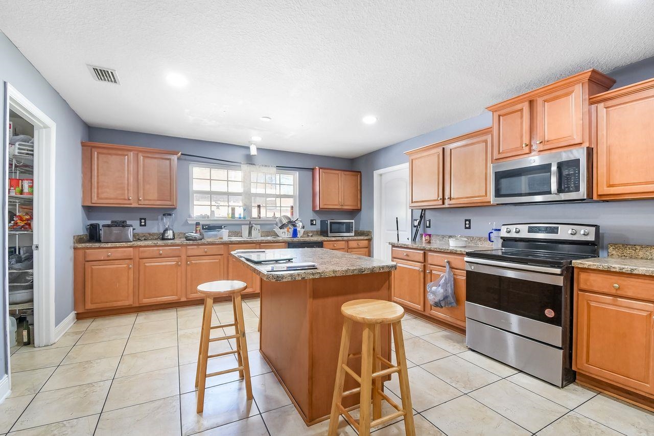 46 Riddle Drive Palm Coast, FL 32164 - Photo 19 of 20 a kitchen with stainless steel appliances granite countertop a stove a sink dishwasher a microwave oven and a refrigerator