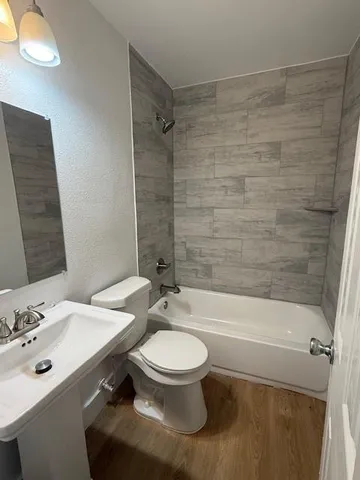 a bathroom with a bathtub shower sink mirror vanity and toilet