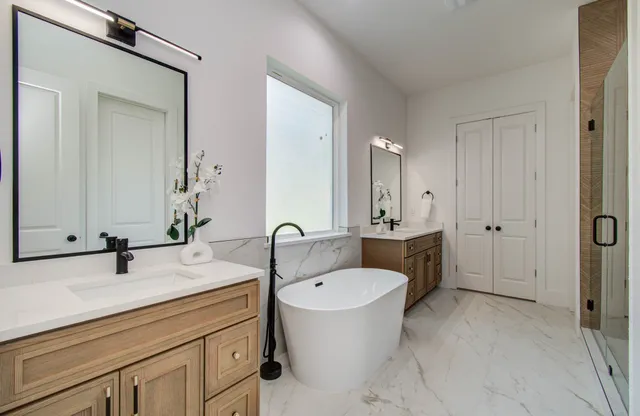 a bathroom with a sink double vanity granite tub shower and mirror