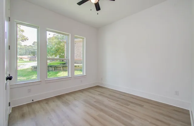 an empty room with a window and a ceiling fan