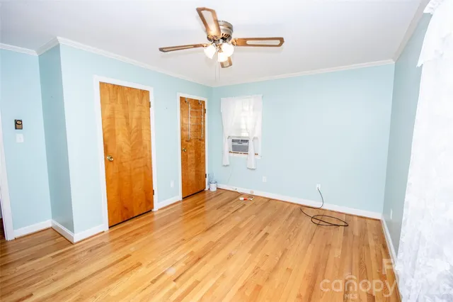 a view of an empty room with wooden floor and a window