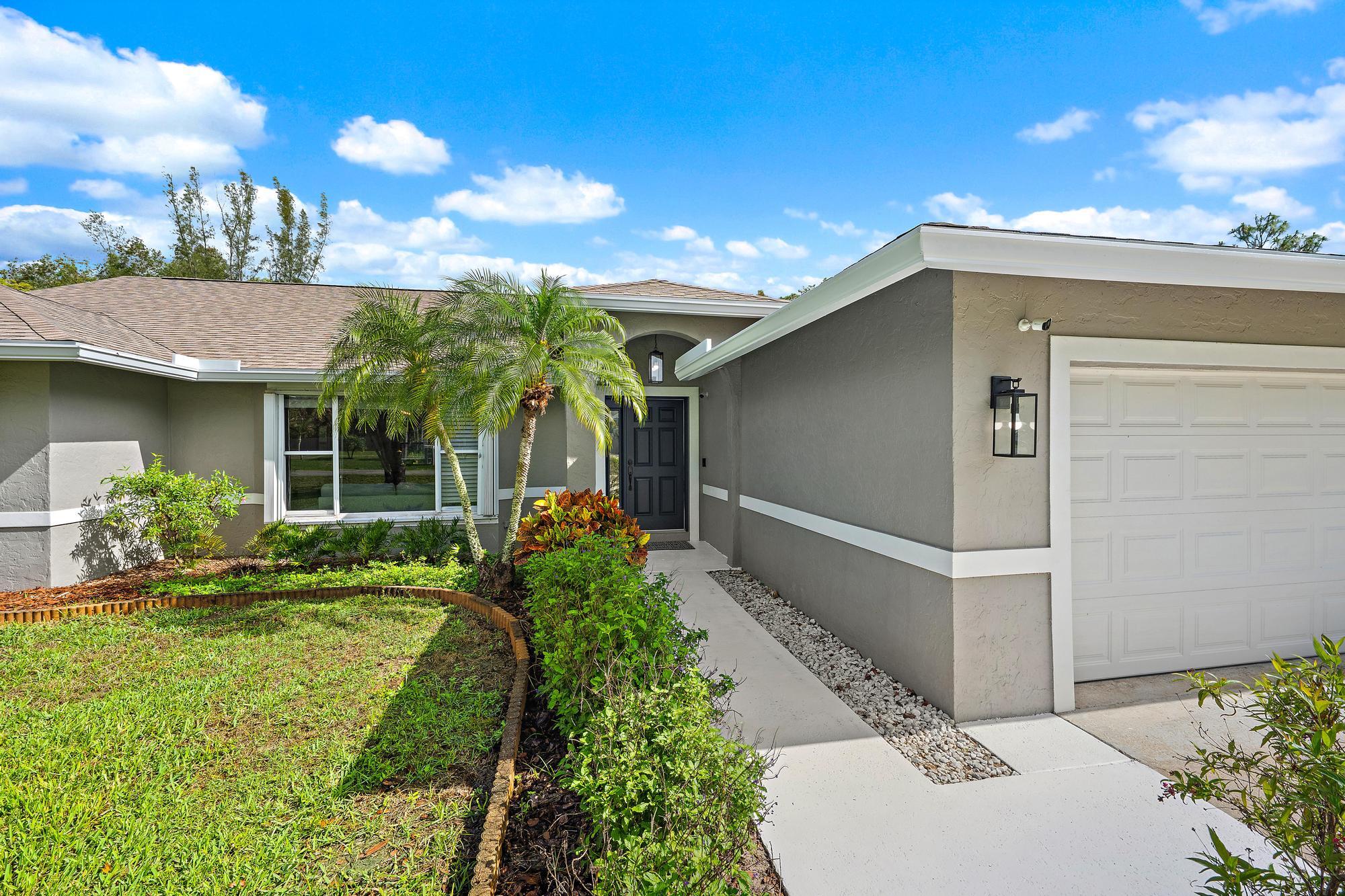 12177 86th Road North West Palm Beach, FL 33412 - Photo 1 of 40 a front view of a house with garden