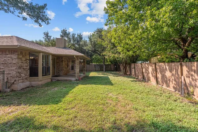 a view of a house with a yard and large tree