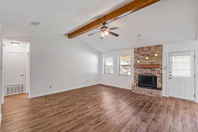 a view of an empty room with a window and wooden floor