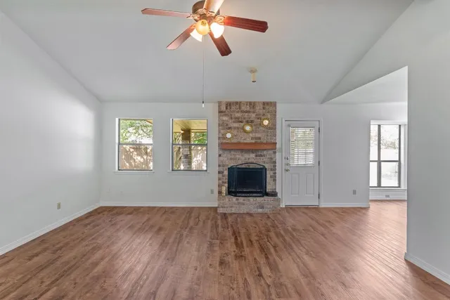 an empty room with windows fireplace and wooden floor
