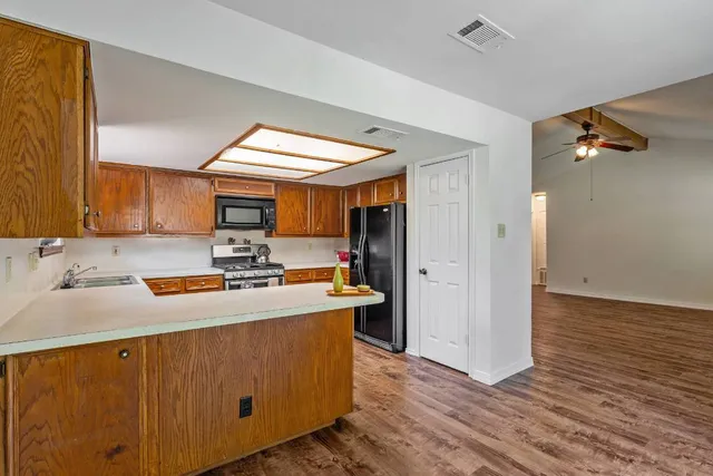a kitchen with stainless steel appliances granite countertop wooden cabinets a stove a sink and a wooden floors