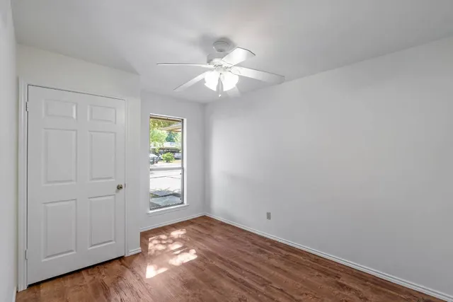 a view of empty room with wooden floor and fan