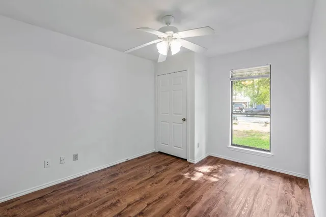 a view of an empty room with wooden floor and a window