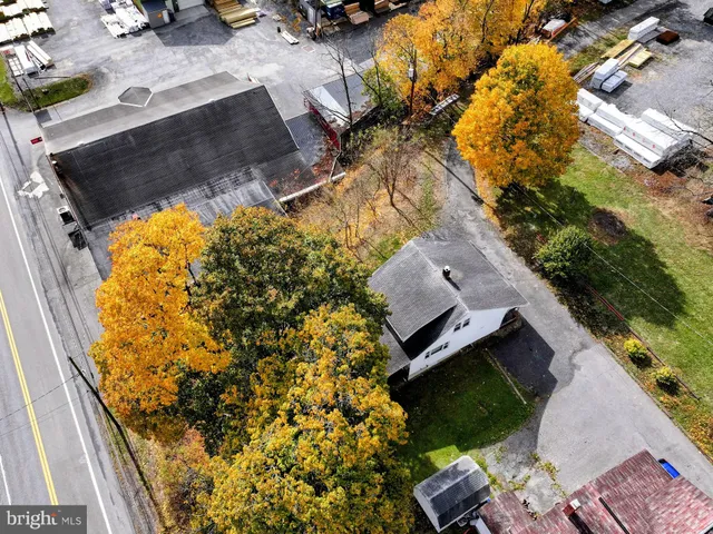 an aerial view of a house with swimming pool and large trees