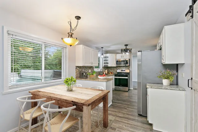 a kitchen with a table chairs a refrigerator and a window