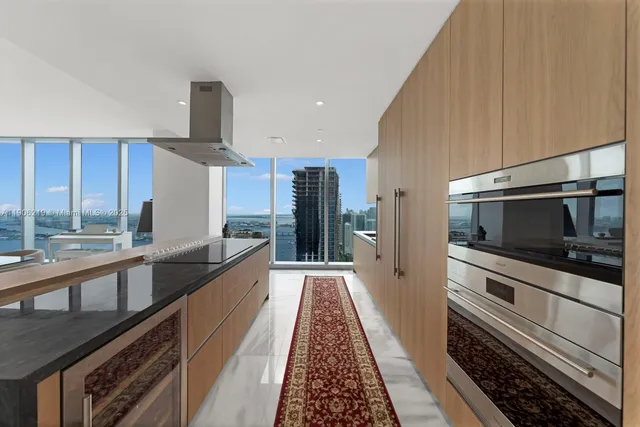 a large kitchen with stainless steel appliances a large counter top a stove and a refrigerator