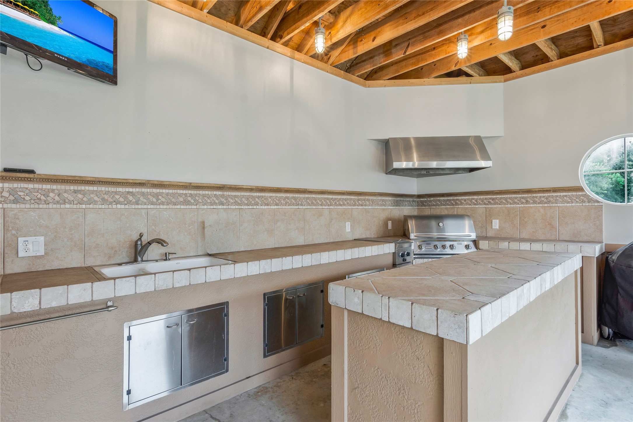 13914 Skinner Road Cypress, TX 77429 - Photo 47 of 50 Covered outdoor kitchen and bar with stainless steel appliances, generous counter space, open shelving, and room to serve guests by the pool.