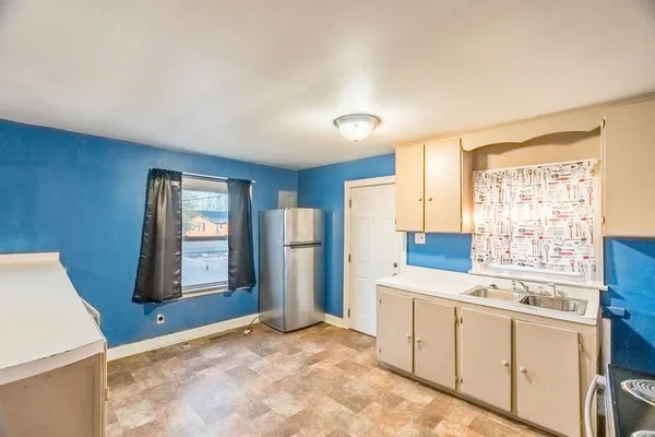 a view of a kitchen with refrigerator and window