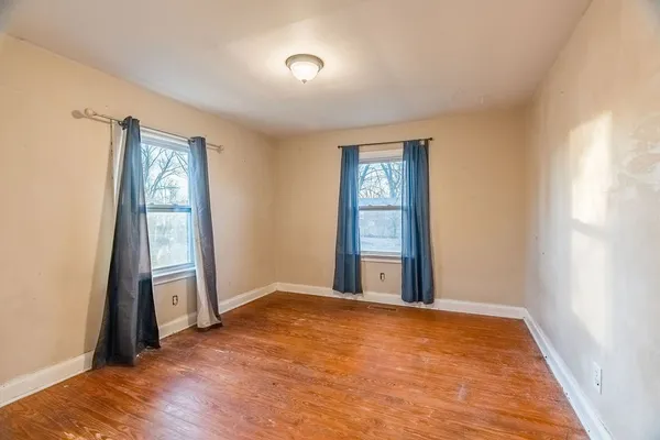 a view of an empty room with window and wooden floor