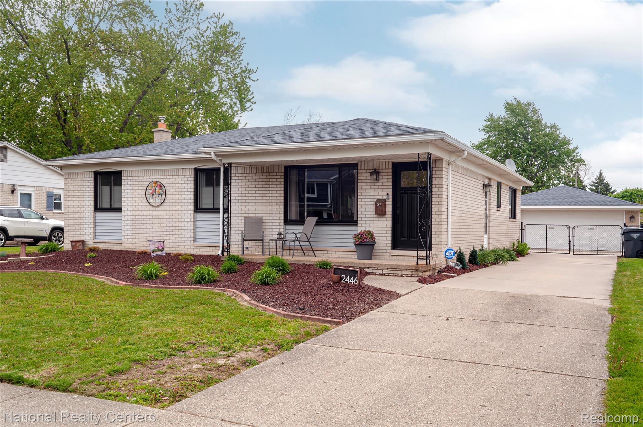 2446 Milverton Road Troy, MI 48083 - Photo 2 of 41 View of front facade with covered porch, a gate, brick siding, a detached garage, and a front lawn