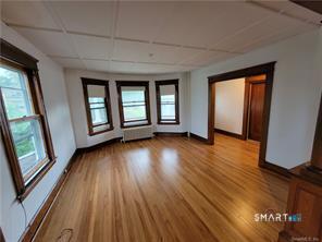 393 Highland Avenue, Unit 2 Waterbury, CT 06708 - Photo 4 of 10 an empty room with wooden floor and windows