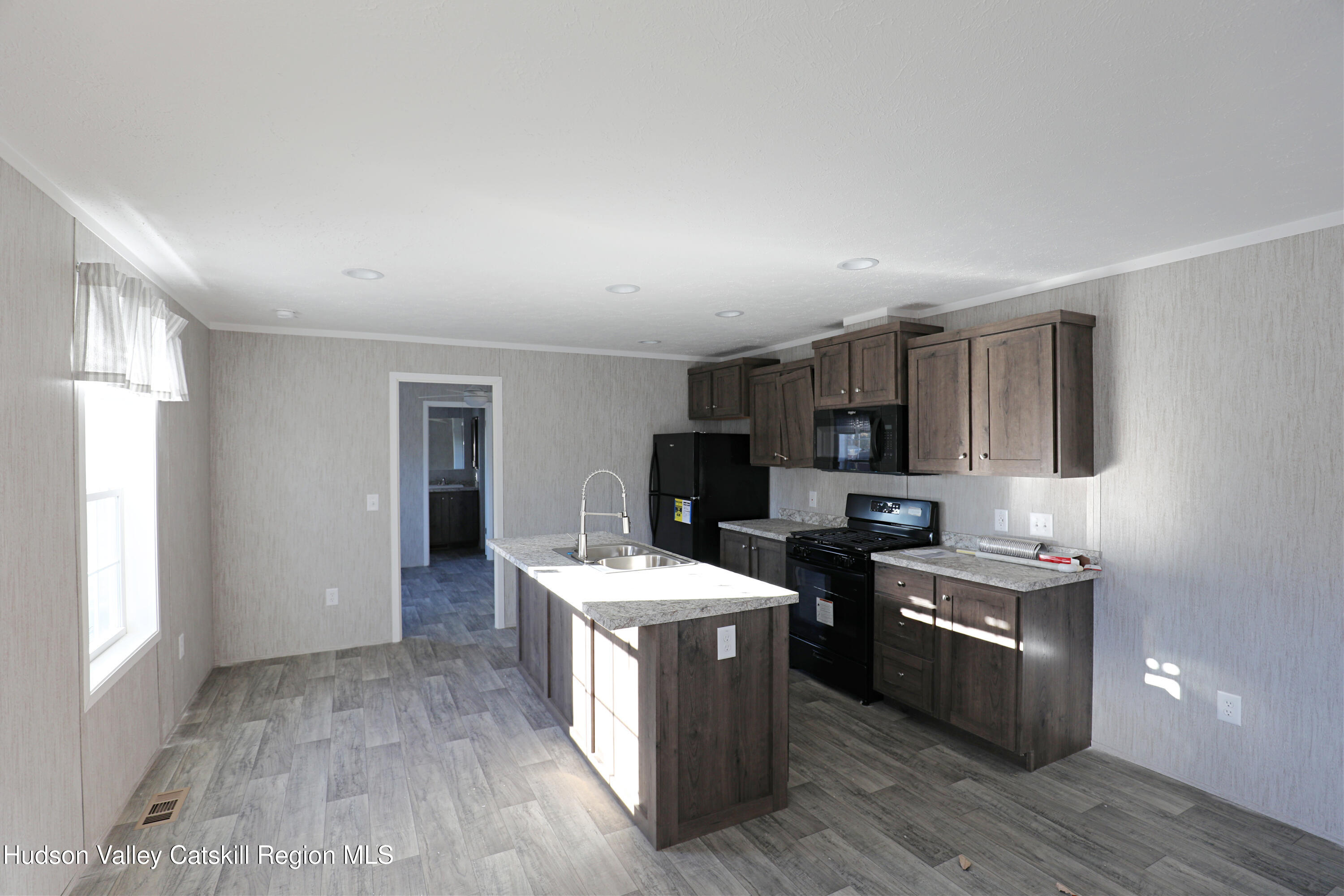 414 Joslen Boulevard, Unit 24 Hudson, NY 12534 - Photo 4 of 9 a kitchen with stainless steel appliances kitchen island hardwood floor sink stove and wooden cabinets