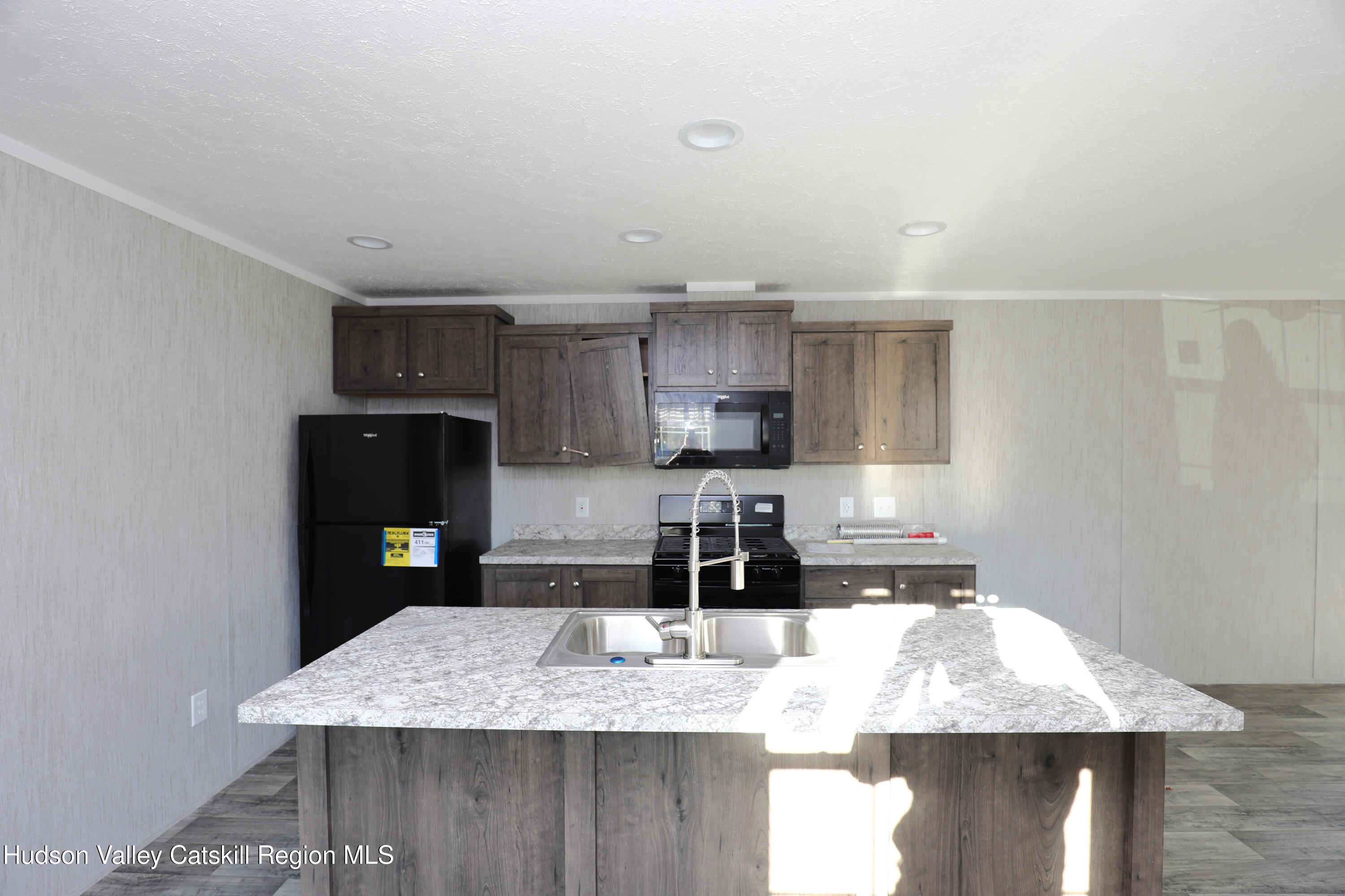 414 Joslen Boulevard, Unit 24 Hudson, NY 12534 - Photo 7 of 9 a kitchen with kitchen island granite countertop a sink a stove and refrigerator