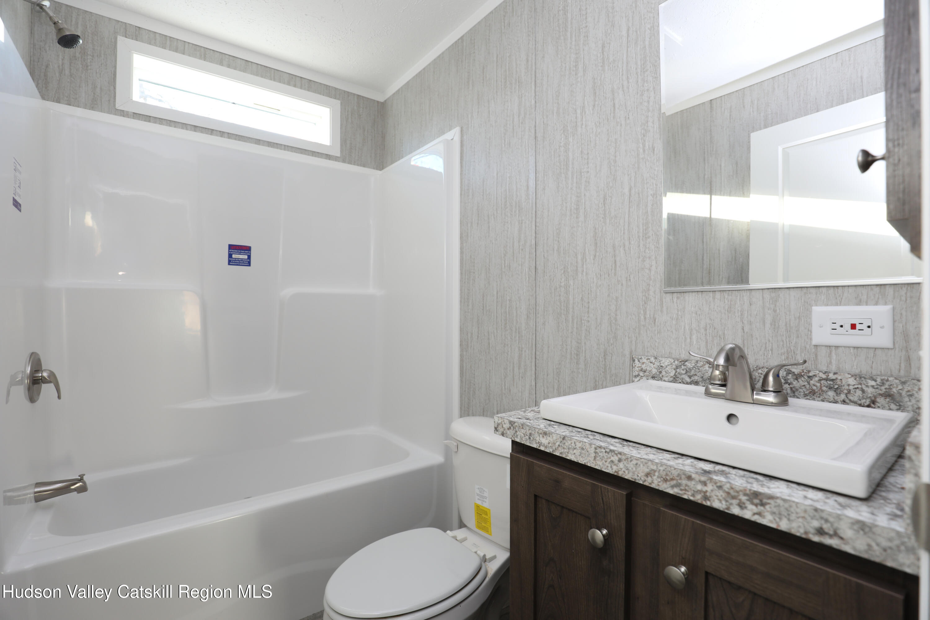 414 Joslen Boulevard, Unit 24 Hudson, NY 12534 - Photo 9 of 9 a bathroom with a granite countertop sink toilet and shower