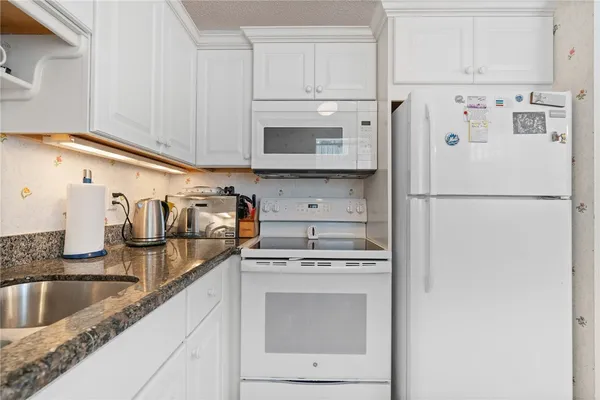 a kitchen with refrigerator a stove a sink and white cabinets
