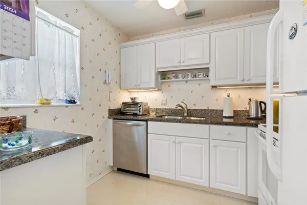 a kitchen with granite countertop white cabinets and white appliances