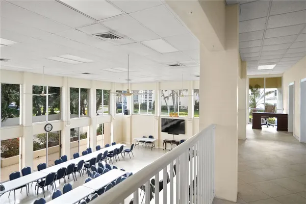 a room with lots of tables a large window and chairs