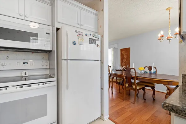 a kitchen with stainless steel appliances a refrigerator a stove a dining table and chairs with wooden floor