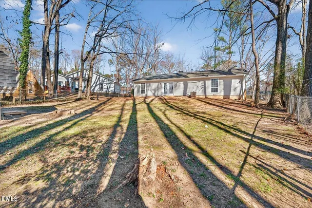 a view of backyard with wooden fence and large trees