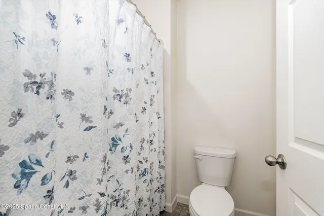 a white toilet sitting next to a shower curtain