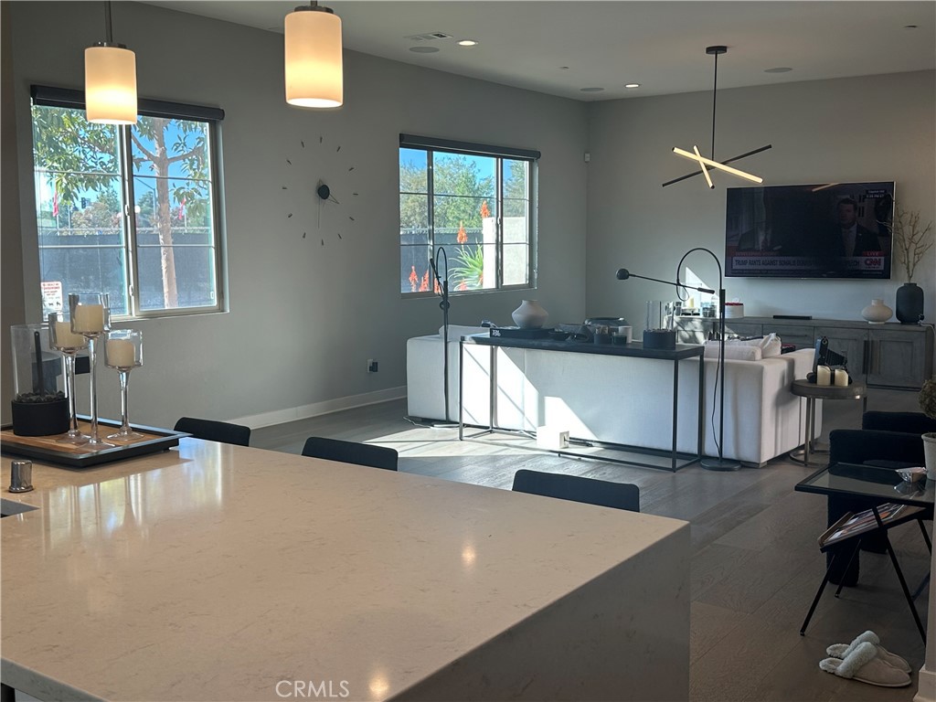 101 Interval Irvine, CA 92618 - Photo 4 of 20 a kitchen with kitchen island granite countertop a stove a sink a dining table and chairs with wooden floor